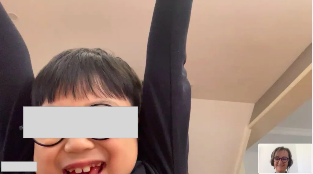 Child raising arms in celebration after winning a French learning game during online class. 